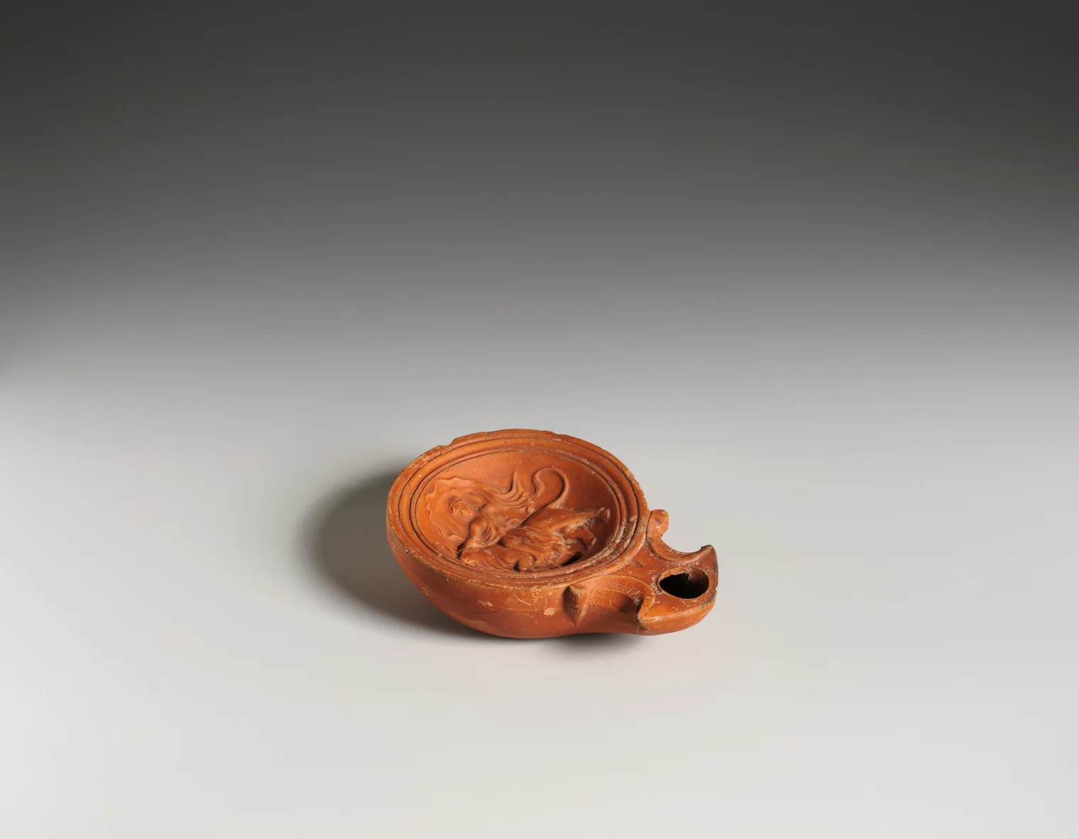 Lucerna romana de terracota con escena de Europa y el toro, vista oblicua