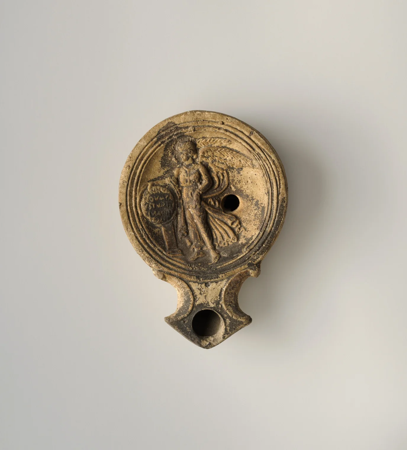 Lucerna romana con relieve de Victoria alada y escudo inscrito, siglo I