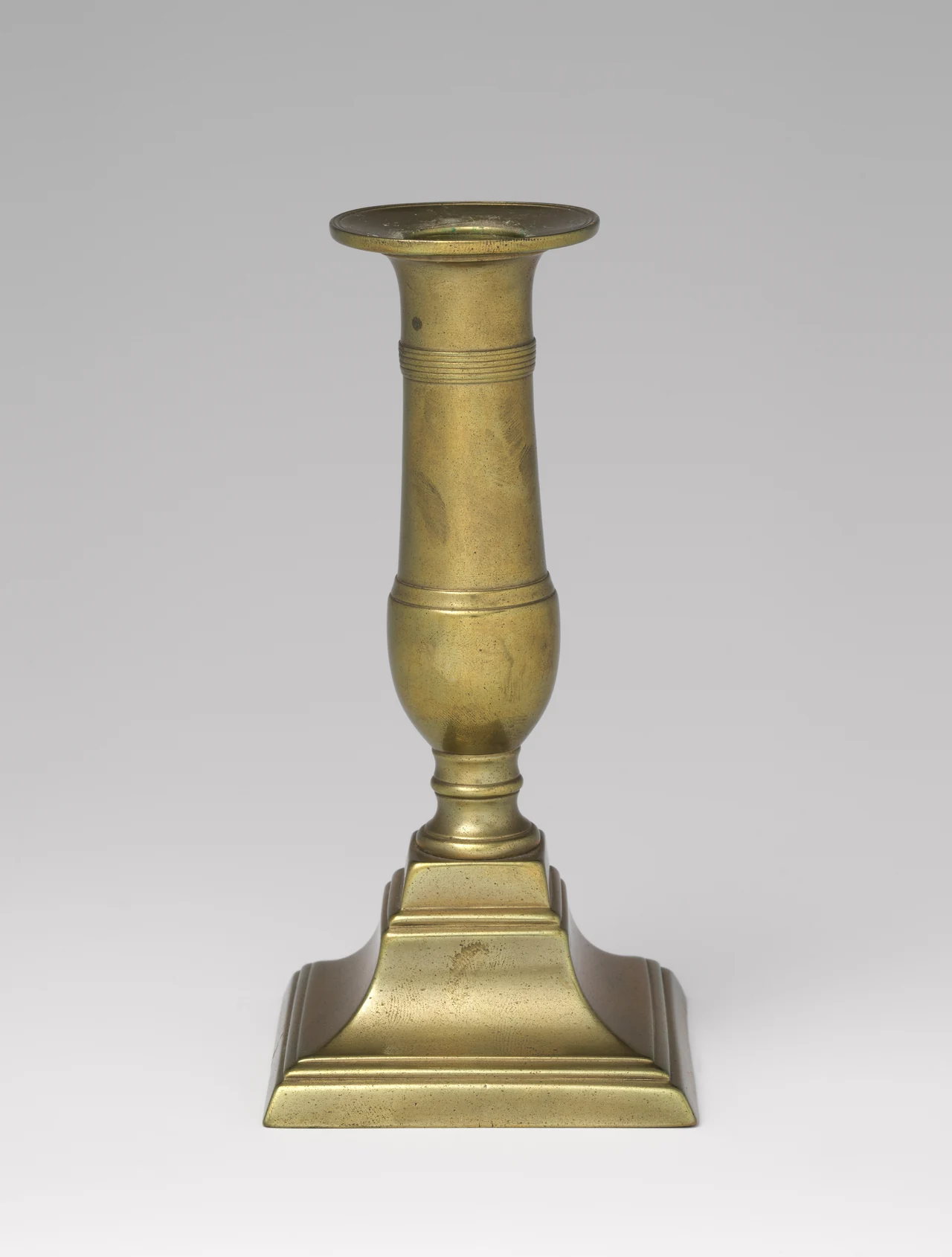 Candelero de latón de 1700 a 1800, con cuerpo moldurado y base cuadrada, conservado en The Metropolitan Museum of Art