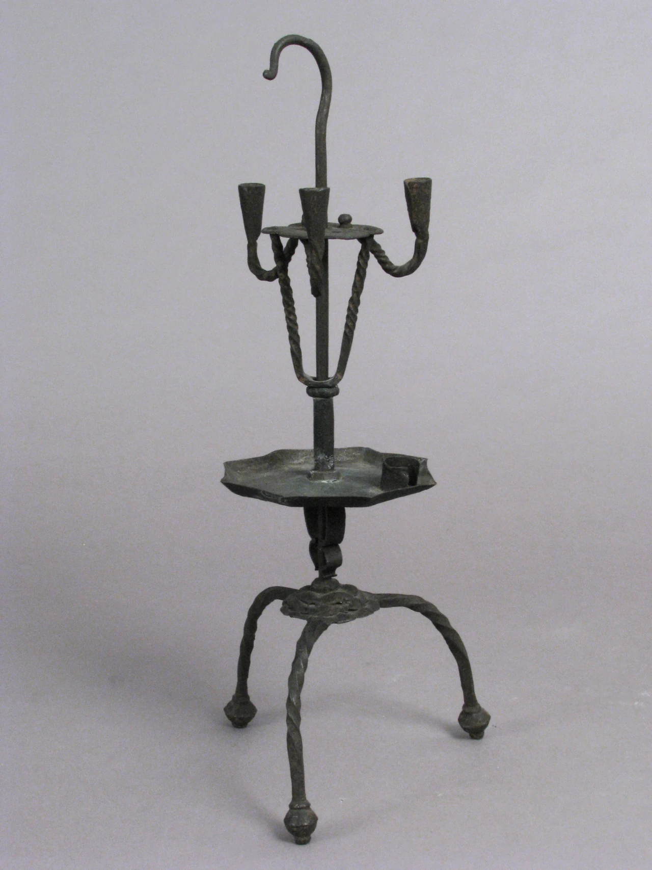 Candelero español de hierro del siglo XVI, con tres portavelas, gancho superior y base de tres patas