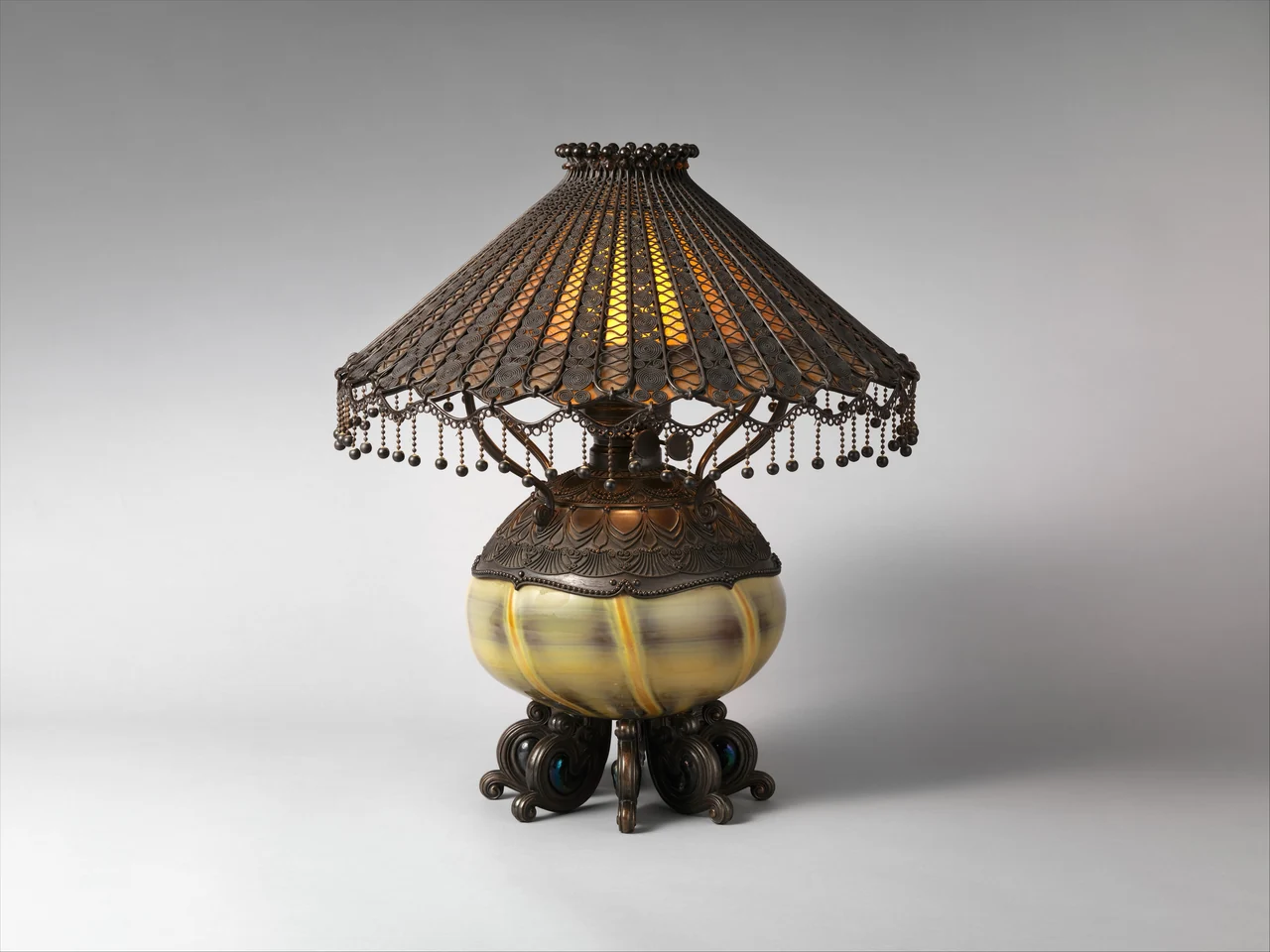 Lámpara de mesa de Tiffany con pantalla de vidrio emplomado, depósito de vidrio soplado y base de bronce patinado