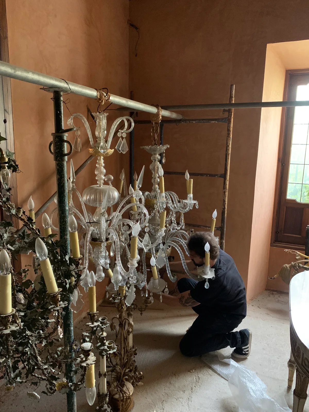 Trabajo de desmontaje de una lámpara de brazos y cristales junto a un andamio en su ubicación.