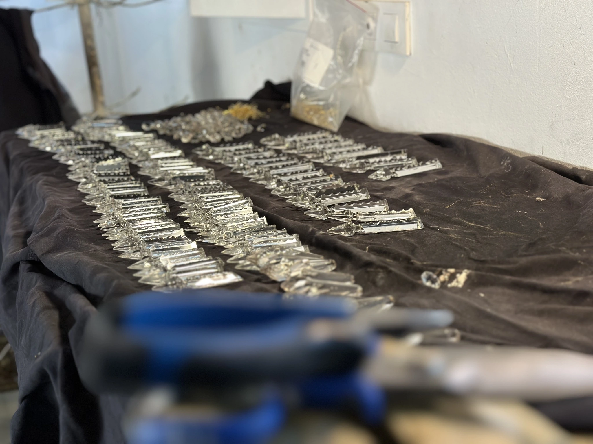 Cristales de lámpara preparados sobre la mesa durante el proceso artesanal de desalambrado en el taller de Lámparas Escala.